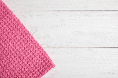 Beyaz ahşap arka plan üzerinde pembe mutfak havlusu, üst görünüm. Metin için alan