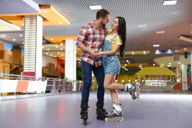 Young couple spending time at roller skating rink clipart