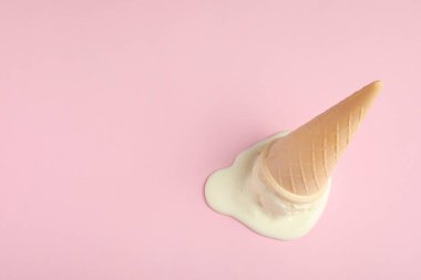 Pembe arka plan üzerinde gofret konisi içinde eritilmiş vanilyalı dondurma, görünümüyukarıda. Metin için alan