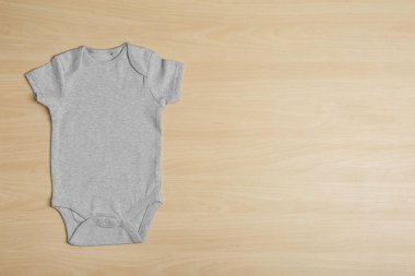 Cute baby onesie on wooden background, top view. Space for text clipart