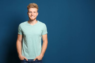 Mavi arka planda boş t-shirt giyen genç adam. Tasarım için mockup