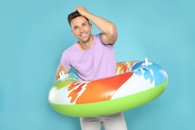 Mavi arka plan üzerinde parlak şişme halka ile Mutlu genç adam