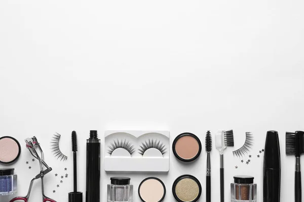 Kompozycja z fałszywymi rzęsami i innymi produktami do makijażu na białym tle, widok z góry — Zdjęcie stockowe