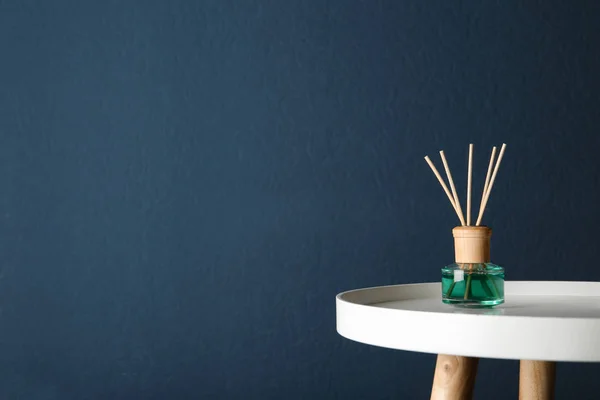 Освежитель воздуха тростника на столе на темно-синем фоне, пространство для текста — стоковое фото