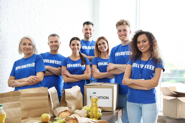 Team ehrenamtlicher Helfer bei Tisch mit Lebensmittelspenden — Stockfoto