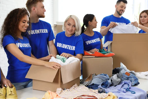 Team van vrijwilligers die donaties verzamelen in dozen binnenshuis — Stockfoto