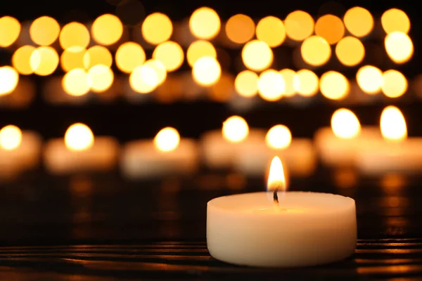 Brennende Kerze auf schwarzem Tisch vor verschwommenem Hintergrund, Platz für Text — Stockfoto