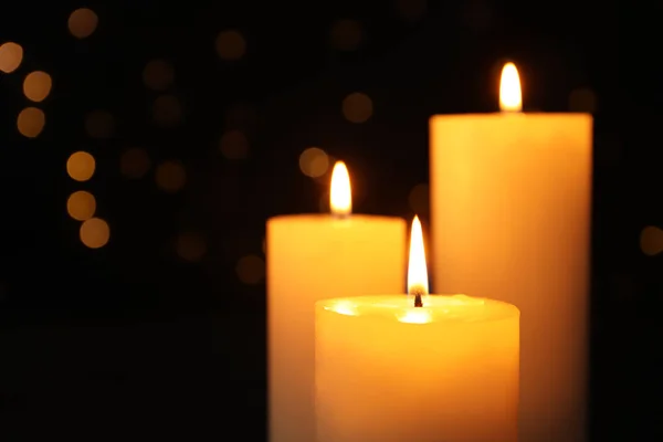 Velas encendidas sobre fondo negro con luces borrosas, espacio para texto — Foto de Stock