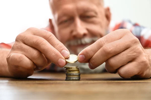 Senior man stacking up coins at table, focus on hand — Stock Photo, Image
