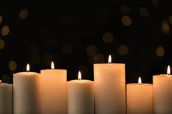 Velas ardientes sobre fondo negro con luces borrosas —  Fotos de Stock