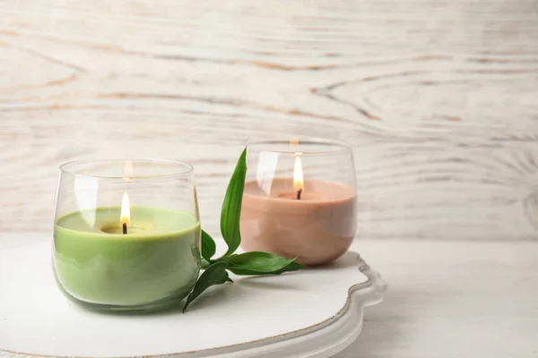 Board with burning candles and bamboo leaves on light table, space for text — Stock Photo, Image