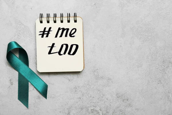 Teal awareness ribbon and notebook with hashtag METOO on grey background, flat lay. Stop sexual assault