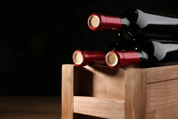 Wooden crate with bottles of wine on dark background, closeup — Stock Photo, Image