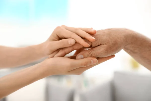 Ludzie trzymając ręce razem na niewyraźne tło, zbliżenie. Pomoc i koncepcja opieki nad osobami starszymi — Zdjęcie stockowe