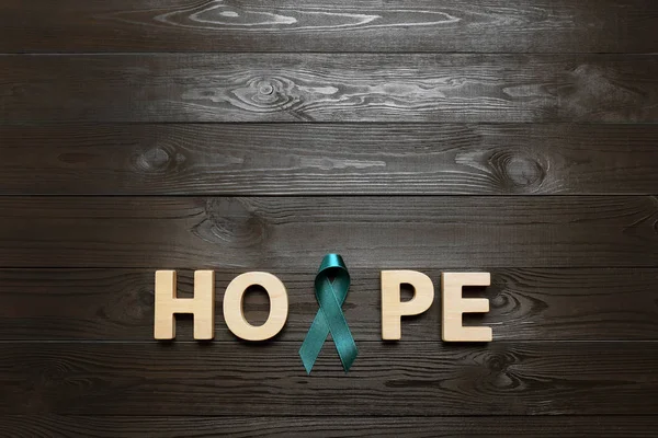Word Hope ahşap arka plan, üst görünümü üzerinde harfler ve teal farkındalık kurdele yapılmış. Sosyal ve tıbbi sorunların sembolü — Stok fotoğraf