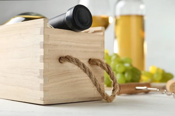 Caixa de madeira com garrafa de vinho na mesa branca — Fotografia de Stock