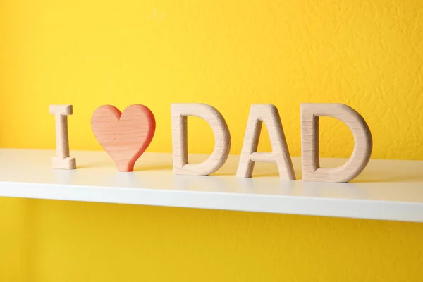 Frase I AMOR DAD feito de letras de madeira na prateleira perto da parede amarela — Fotografia de Stock