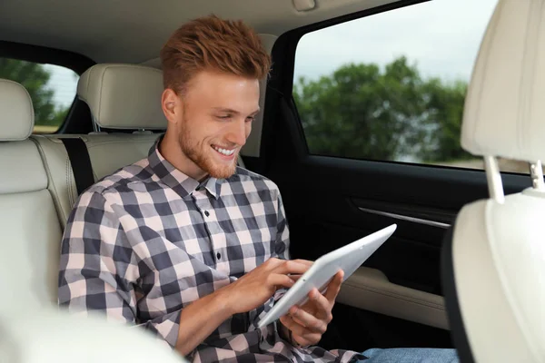 Ελκυστικός νέος άνθρωπος χρησιμοποιώντας tablet σε πολυτελές αυτοκίνητο — Φωτογραφία Αρχείου