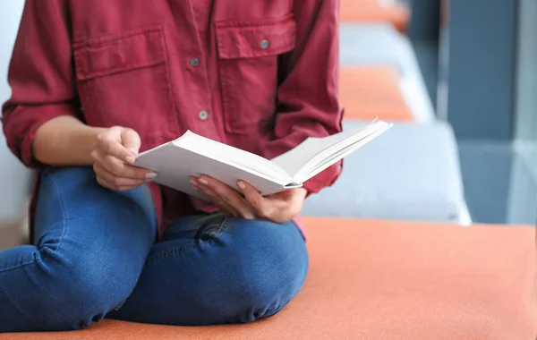 Młoda kobieta czytania książki w bibliotece, zbliżenie — Zdjęcie stockowe