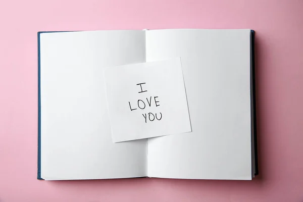 Stück Papier mit Phrase i love you und Notizbuch auf rosa Hintergrund, Ansicht von oben — Stockfoto