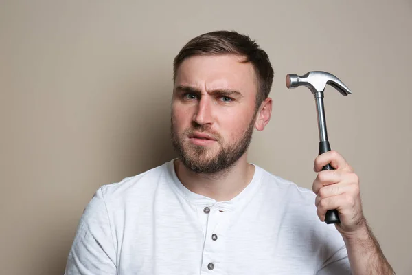 Young working man with hammer on beige background — Stock Photo, Image