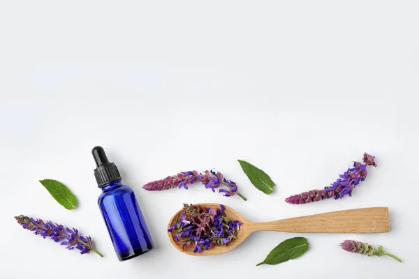 Composizione con bottiglia di olio essenziale di salvia e fiori su fondo bianco, vista dall'alto — Foto Stock