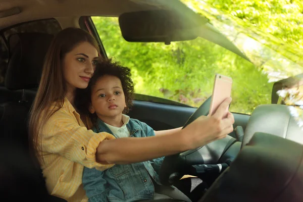 Küçük kızı olan bir anne araba kullanıyor ve selfie çekiyor. Çocuk tehlikede — Stok fotoğraf