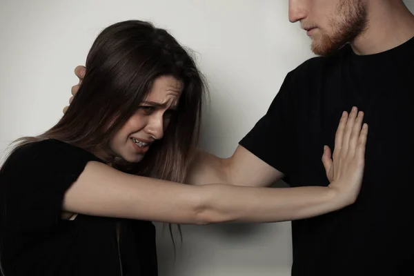Mann kämpft mit Frau auf hellem Hintergrund. Stoppt sexuelle Übergriffe — Stockfoto