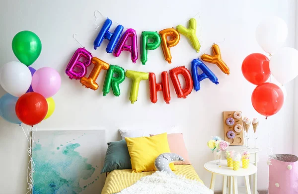Frase de aniversário feliz feito de letras de balão coloridas e mesa com guloseimas no quarto moderno — Fotografia de Stock