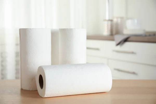 Rolls of paper towels on wooden table in kitchen. Space for text