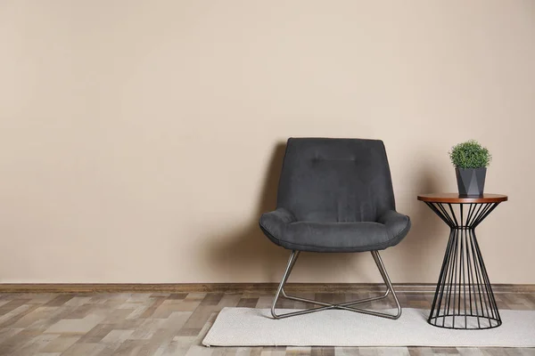Interior elegante quarto com cadeira confortável e planta na mesa lateral perto da parede de cor. Espaço para texto — Fotografia de Stock