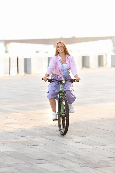 Young woman riding bicycle in city on sunny day — Stock Photo, Image