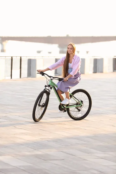 Молода жінка їде на велосипеді в місті в сонячний день — стокове фото
