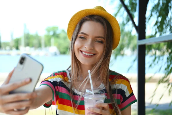 Feliz joven con bebida tomando selfie en el parque — Foto de Stock