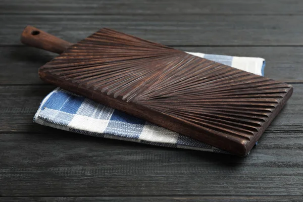 Toalla de cocina y tabla de cortar en mesa de madera negra — Foto de Stock