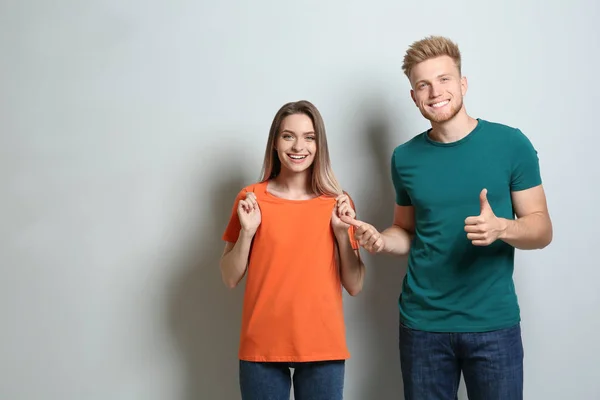 Mladí manželé nosí prázdné trička na světlém pozadí. Mockup pro design — Stock fotografie