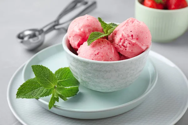 Delicioso sorvete rosa com hortelã na tigela na mesa — Fotografia de Stock