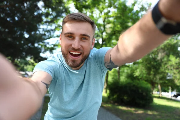 Happy young man taking selfie in park — Stock Photo, Image