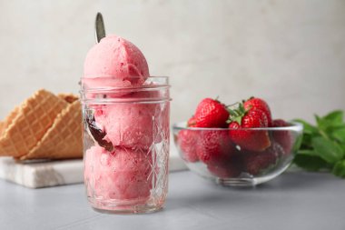 Gri masada çilek ile servis edilen lezzetli pembe dondurma