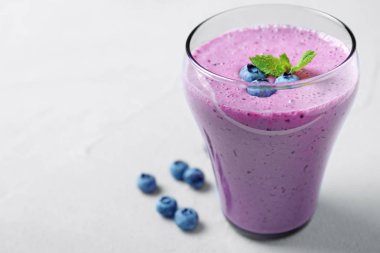 Açık gri masada lezzetli yaban mersini Smoothie bir bardak. Metin alanı
