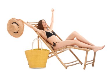 Beyaz arka plana karşı şezlongüzerinde çanta ile genç bir kadın. Plaj aksesuarları