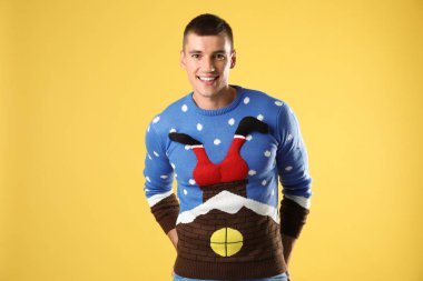 Sarı arka plan üzerinde Noel kazak mutlu genç adam Portresi