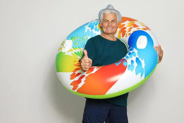 Funny mature man with bright inflatable ring on light background — Stock Photo, Image