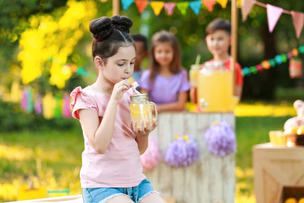 Linda niña bebiendo limonada natural en el parque, espacio para el texto. Bebida refrescante de verano — Foto de Stock