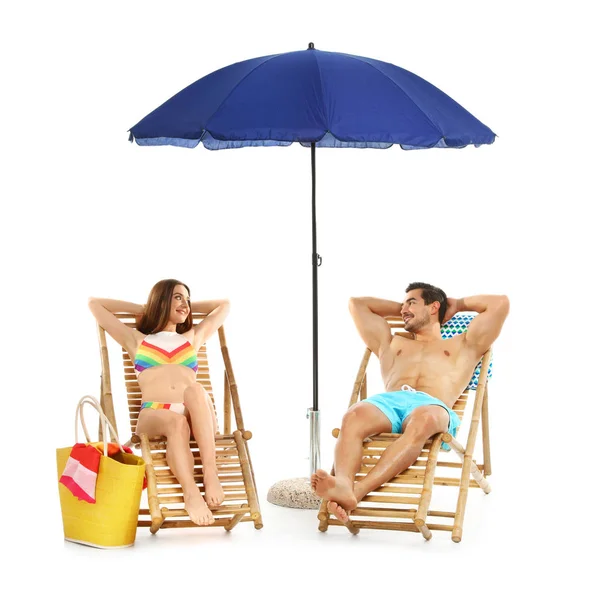 Coppia giovane con accessori da spiaggia su lettini su sfondo bianco — Foto Stock