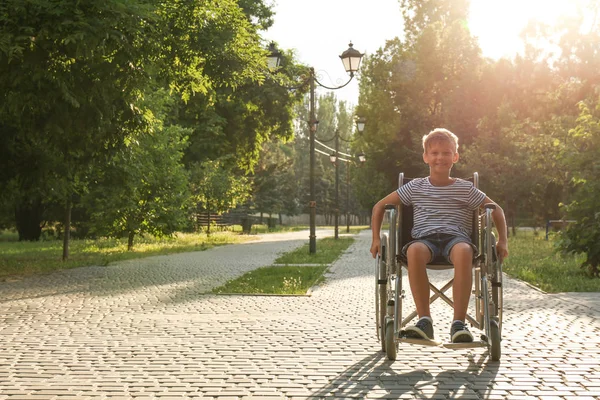 Menino feliz em cadeira de rodas no parque no dia ensolarado. Espaço para texto — Fotografia de Stock