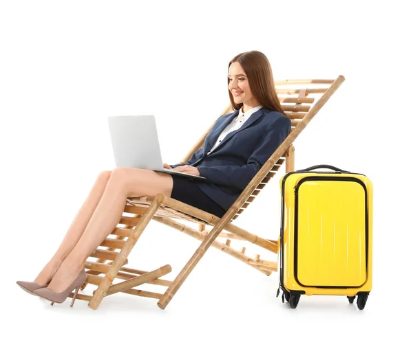 Молодая деловая женщина с ноутбуком и чемоданом на шезлонге на белом фоне. Аксессуары — стоковое фото