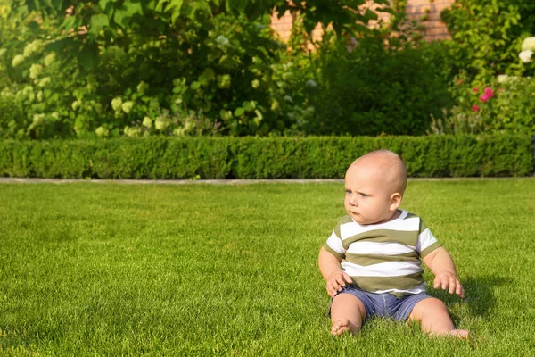 Sevimli küçük bebek açık havada yeşil çim en iyi şekilde oturuyor — Stok fotoğraf