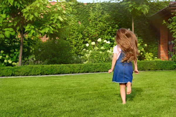 Gadis kecil lucu berjalan di taman hijau pada hari musim panas — Stok Foto