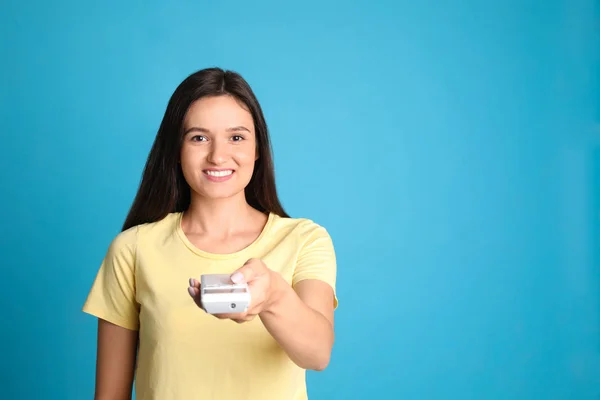 Feliz joven mujer que opera el aire acondicionado con control remoto sobre fondo azul claro. Espacio para texto — Foto de Stock